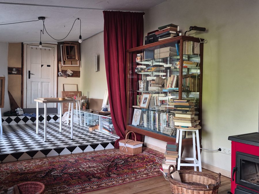 Wohnraum mit Bücherregal, Kaminofen und Schachbrettboden